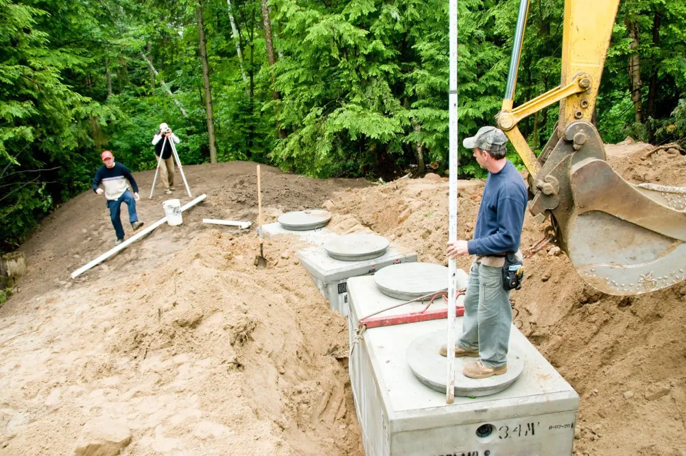 Crew setting concrete septic tanks into an excavated trench